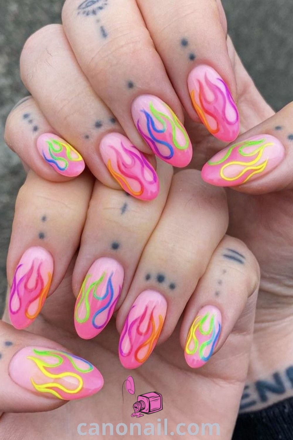 Spring nails featuring bright and neon colors on almond-shaped nails with funky designs, nail charms, and festive elements. A beautiful and trendy manicure idea for the season. Discover more nail inspiration at canonail.com.